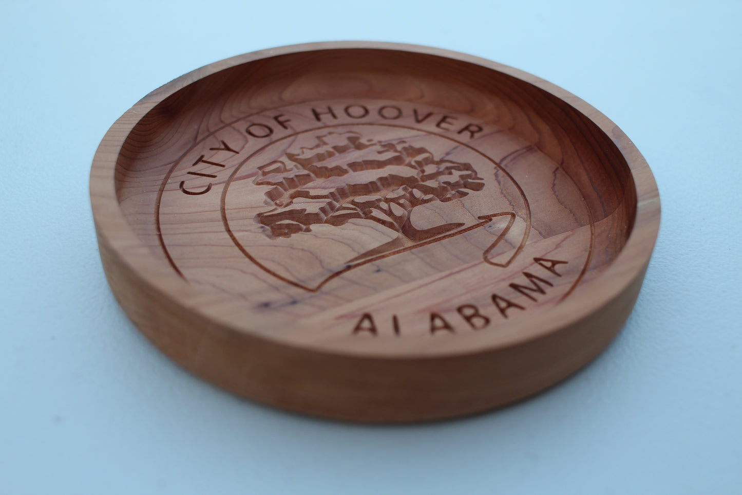 Wooden bowl with 'City of Hoover, Al, Alabama' engraving on a light blue background